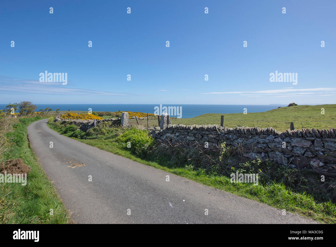 Countryside road in rural location with stone wall and seaview on Anglesey coastal area,North