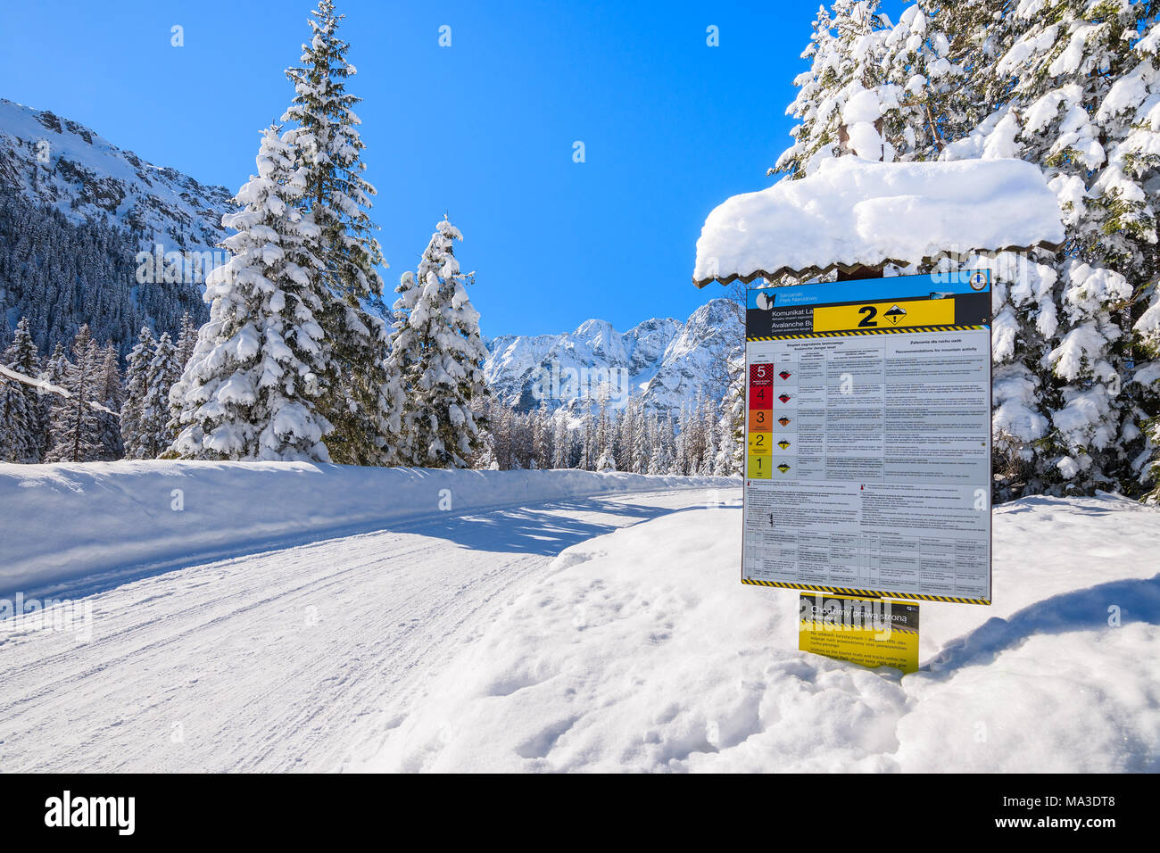 TATRA MOUNTAINS, POLAND - MAR 22, 2018: Sign informing of avalanche risk on road to Morskie Oko lake in winter time. This place is most popular touris Stock Photo
