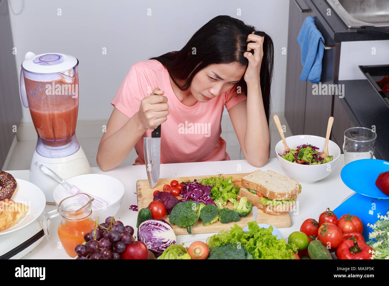 depressed young woman cooking with knife in kitchen room Stock Photo ...