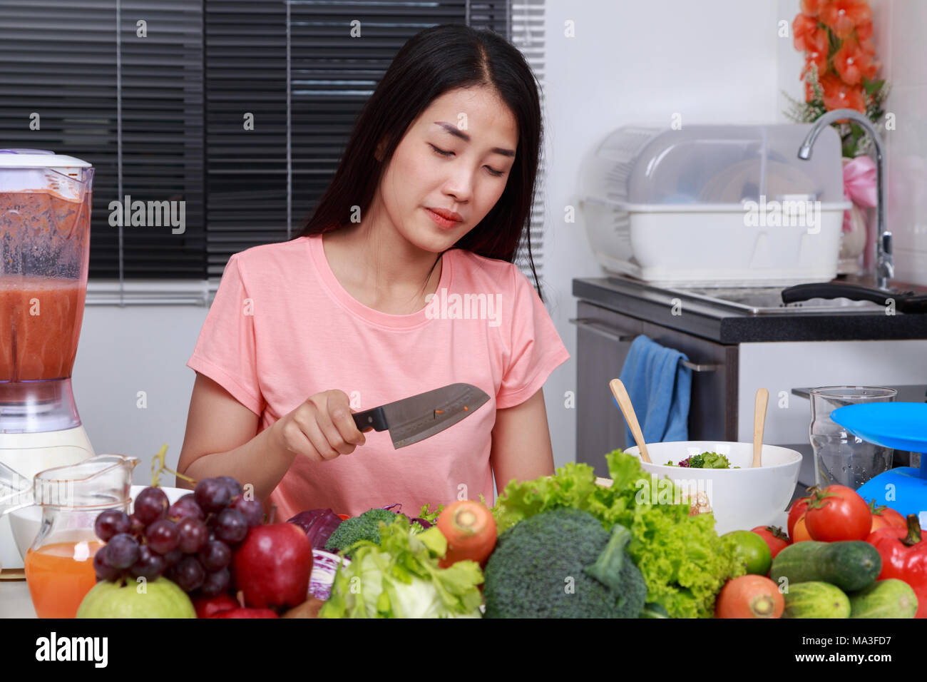 depressed young woman cooking with knife in kitchen room Stock Photo ...