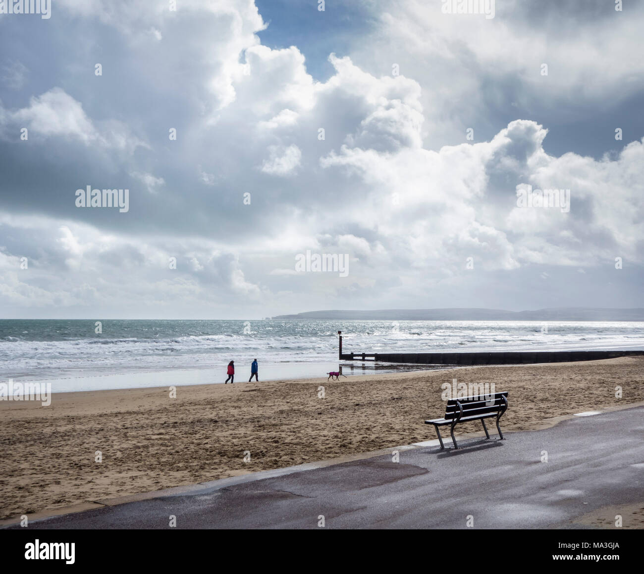 Bournemouth, UK. 29th March 2018. Dog walkers with sunshine and showeres sweeping over Poole Bay. ©dbphots/Alamy Live News Stock Photo