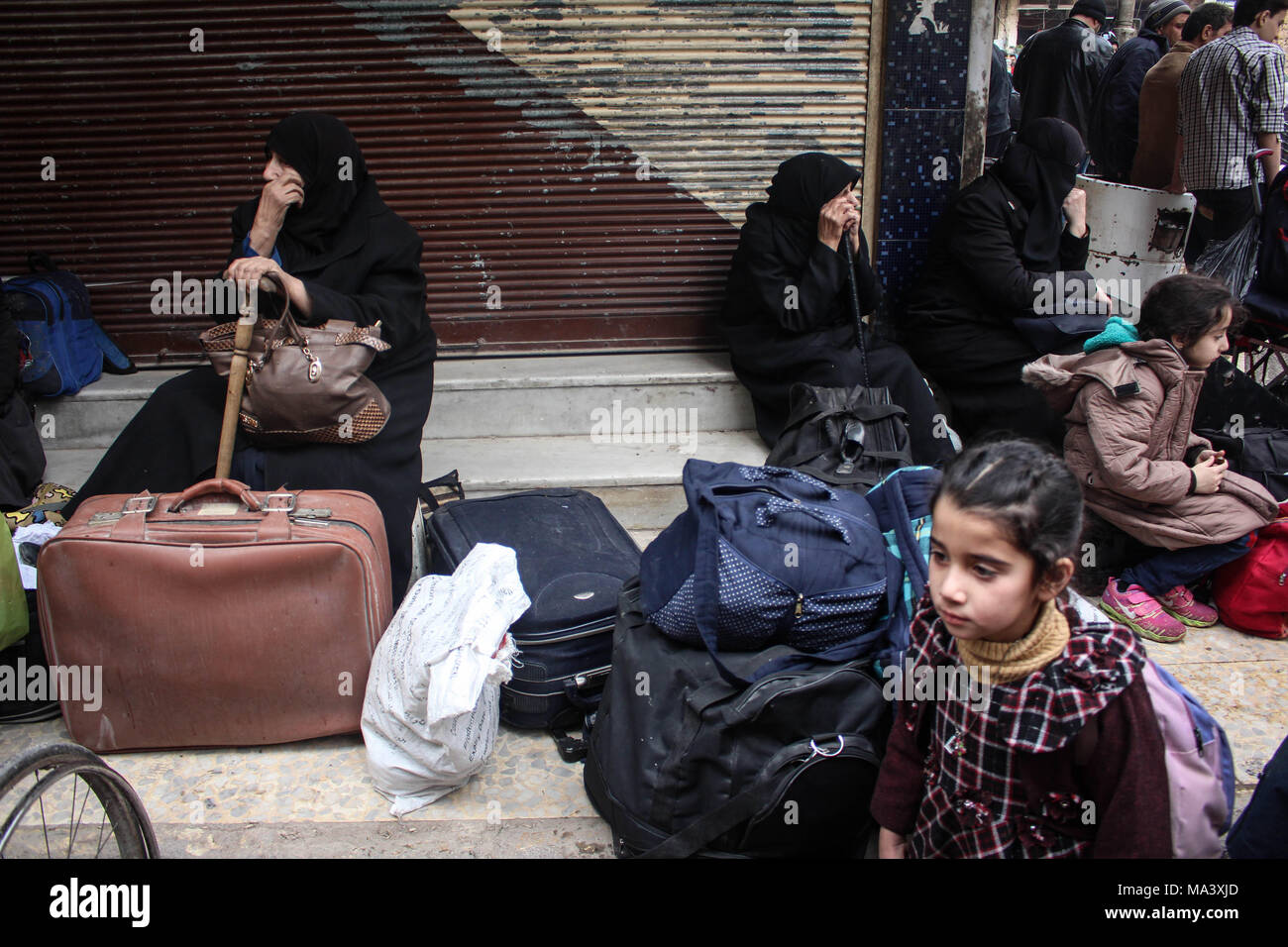 Douma, Syria. 28th Mar, 2018. Women and children seen with their luggages waiting for the evacuation bus.According to reports, civilians, mostly ill people and injured that need urgent medical attention, were evacuated from rebels-held areas in Eastern Ghouta to Damascus under the supervision of the Syrian Arab Red Crescent Credit: Muhmmad Al-Najjar/SOPA Images/ZUMA Wire/Alamy Live News Stock Photo