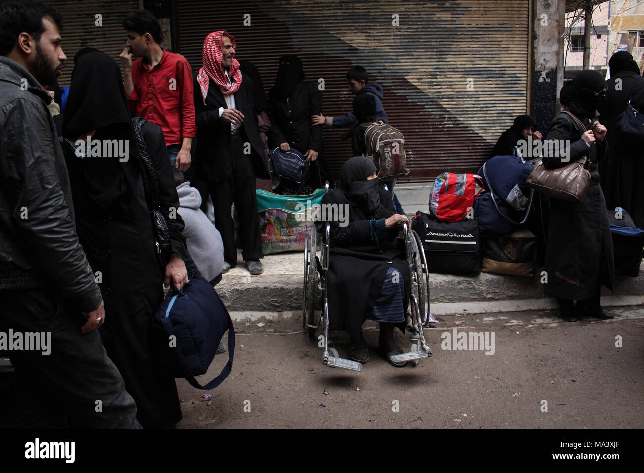 Douma, Syria. 28th Mar, 2018. A disabled woman seen waiting for the evacuation bus.According to reports, civilians, mostly ill people and injured that need urgent medical attention, were evacuated from rebels-held areas in Eastern Ghouta to Damascus under the supervision of the Syrian Arab Red Crescent Credit: Muhmmad Al-Najjar/SOPA Images/ZUMA Wire/Alamy Live News Stock Photo