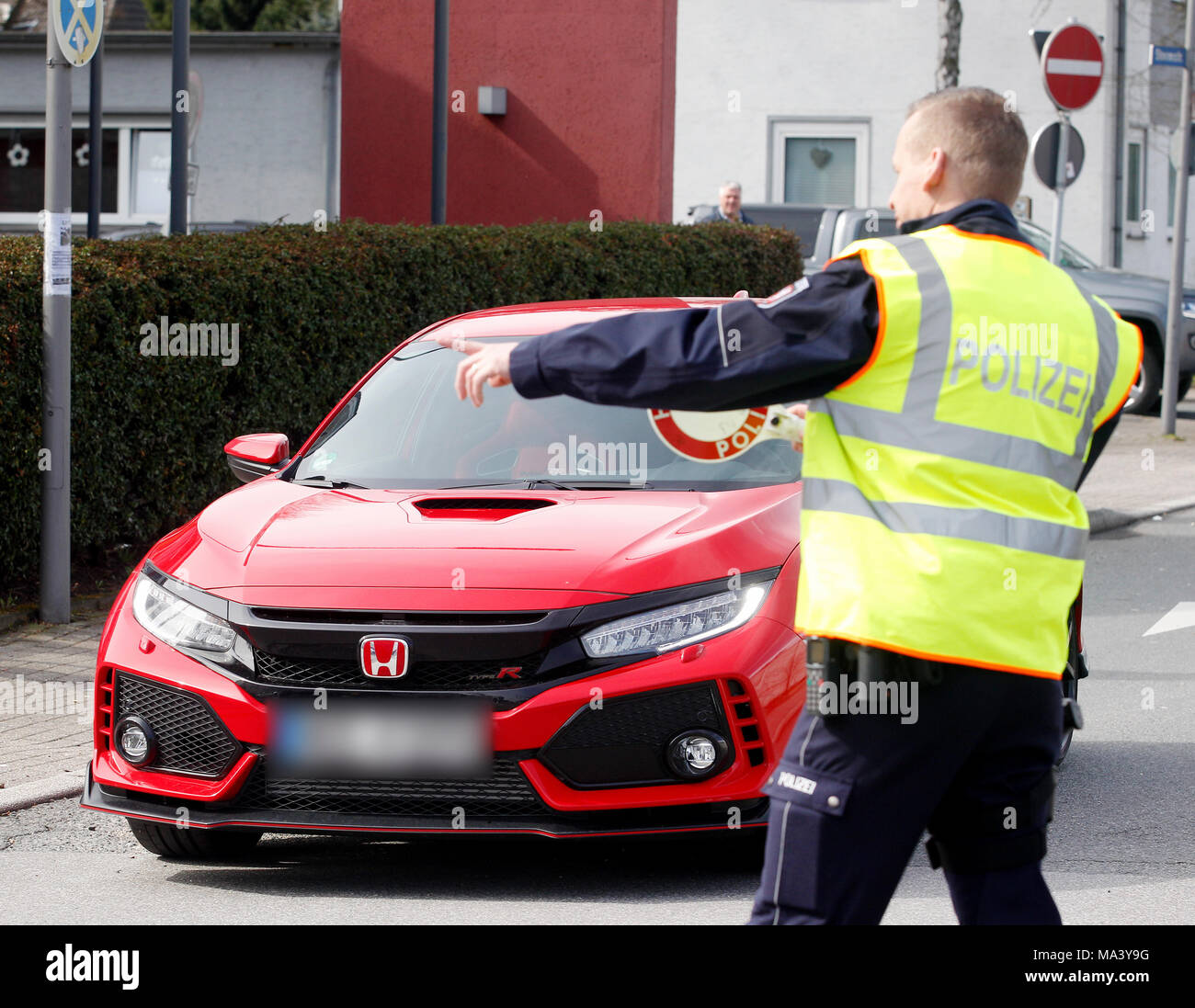 30 March 2018, Germany, Bochum: A police office checks a car at a large meet-up of car tuners. Photo: Roland Weihrauch/dpa - ATTENTION EDITORS: Licence plate blurred for legal reasons. Stock Photo