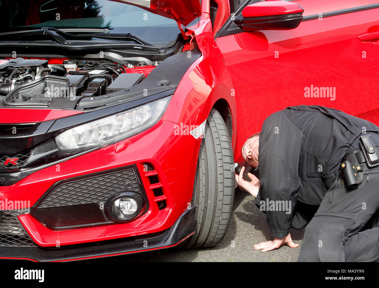 30 March 2018, Germany, Bochum: A police officer checks a car at a large meet-up of car tuners. Photo: Roland Weihrauch/dpa - ATTENTION EDITORS: License plate blurred for legal reasons. Stock Photo