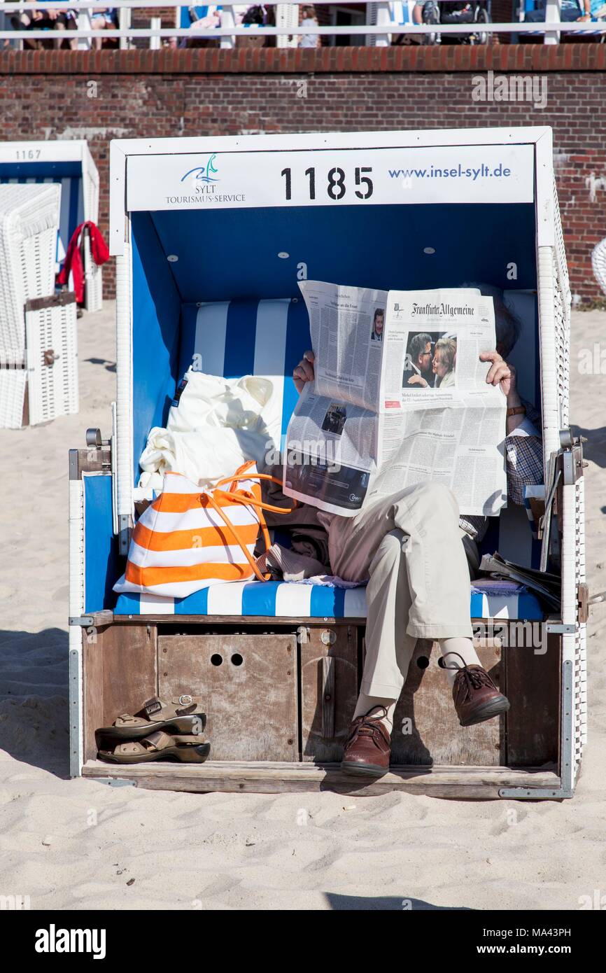 A person reading a newspaper on the beach of Westerland, Sylt, Germany Stock Photo