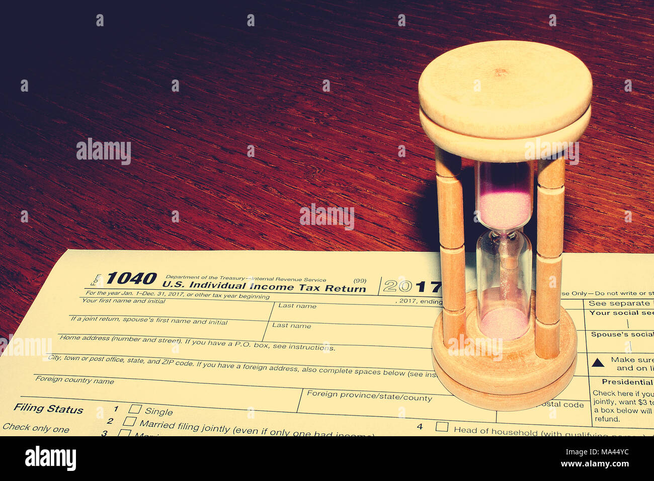 Tax day. The tax form 1040 and hourglass is on a wooden table. Stock Photo