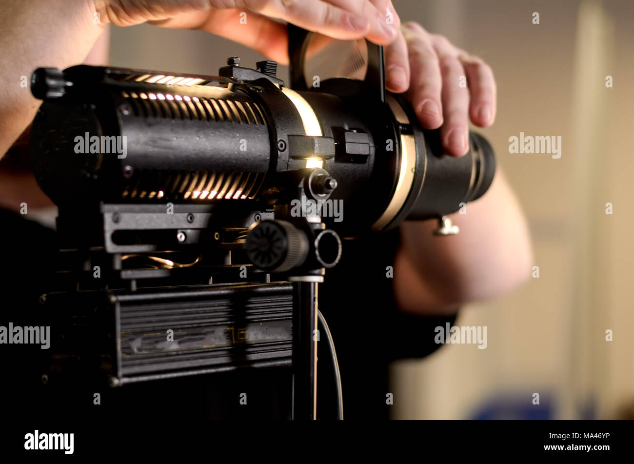 Man adjusts professional film spotlight bulb in studio. Precision lighting instruments in action. Stock Photo