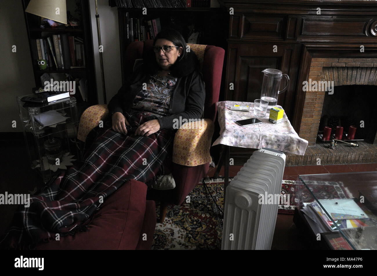 woman sitting in the armchair with her legs covered with a blanket Stock Photo