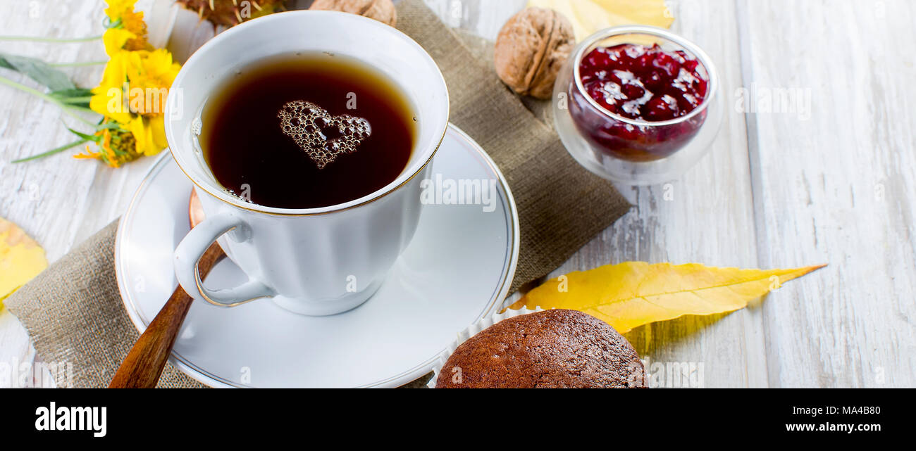 Autumn still life. tea party autumn day cup of tea, cake, nuts, leaves, flowers. Foam in the form of the heart. Copy space. Stock Photo