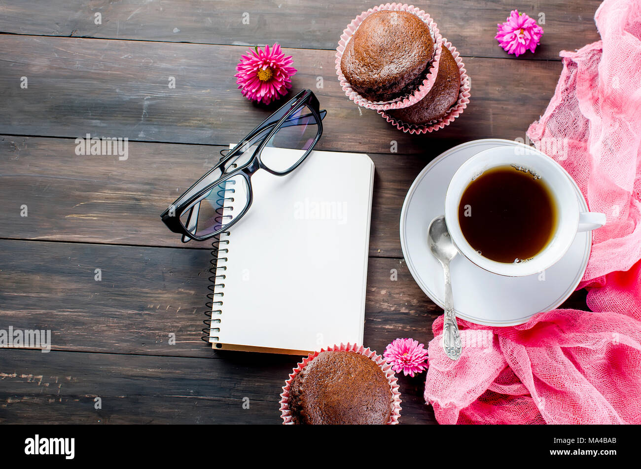chocolate muffins and a cup of coffee breakfast and planning a day of a notebook, still life on a dark wooden table. Copy space, top view. Stock Photo