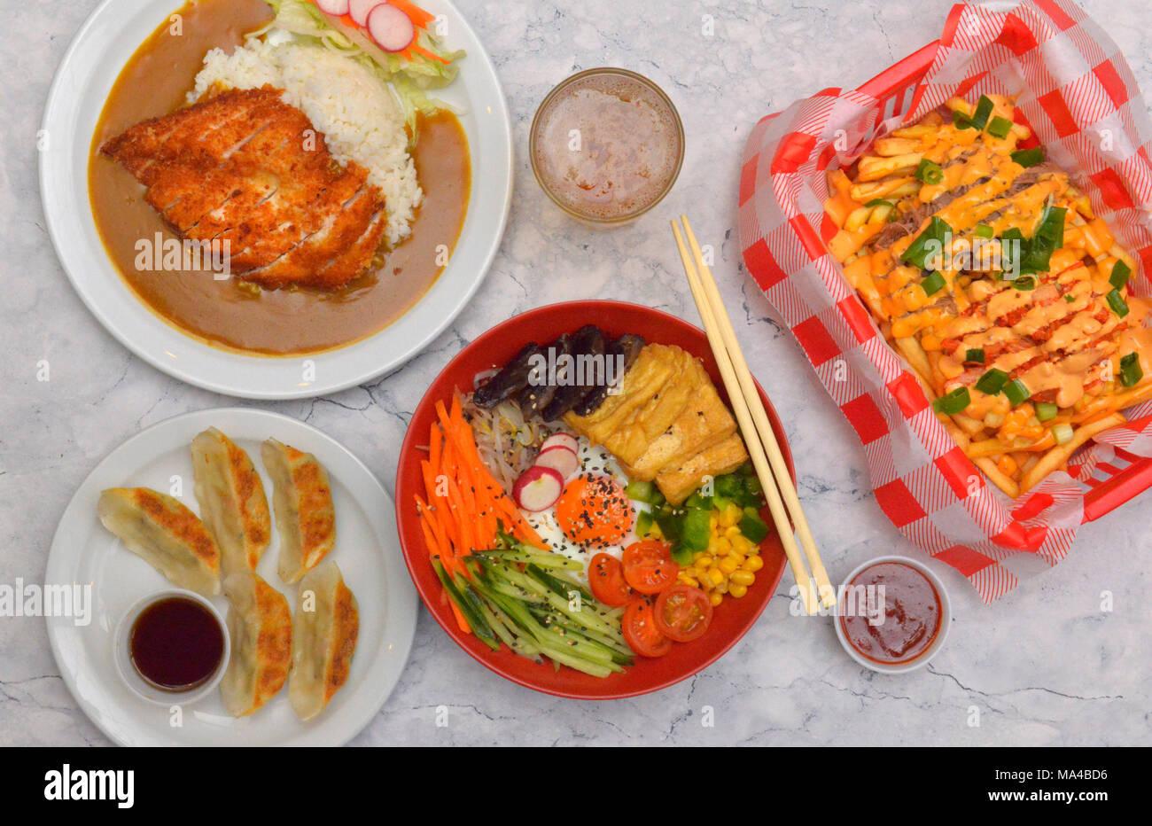 A selection of Korean food including tofu & mushroom bimbimbap, beef kimchi, chicken red curry, vegetable dumplings, crispy panko chicken katsu curry. Stock Photo