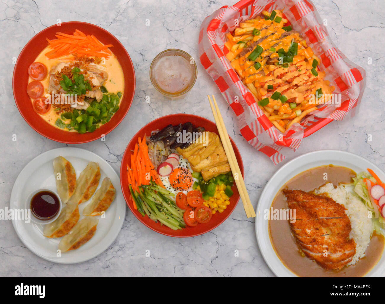 A selection of Korean food including tofu & mushroom bimbimbap, beef kimchi, chicken red curry, vegetable dumplings, crispy panko chicken katsu curry. Stock Photo