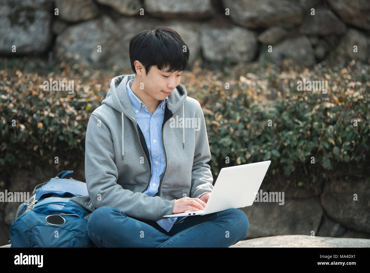 Asian man backpacking using laptop Stock Photo