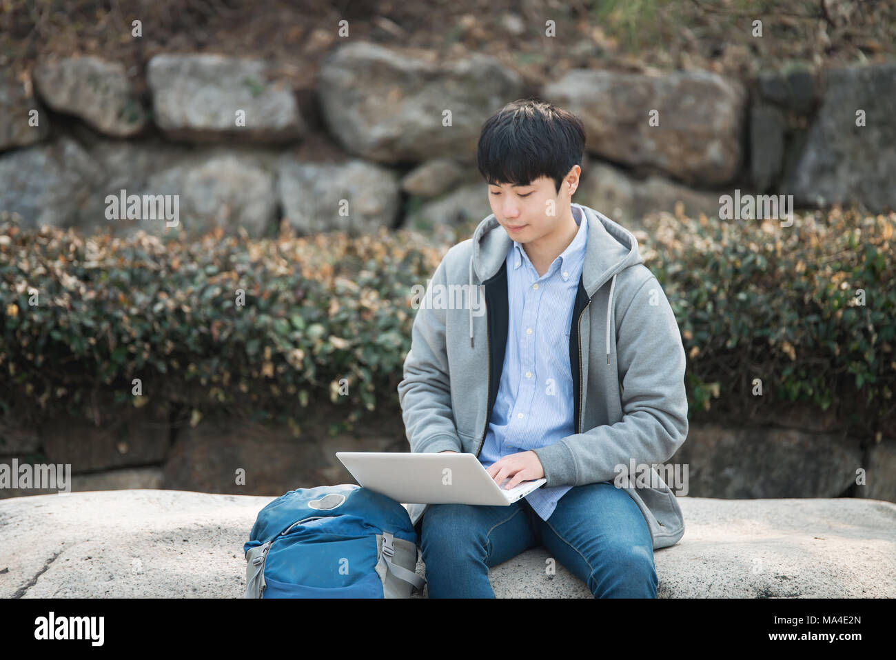 Asian man backpacking using laptop Stock Photo