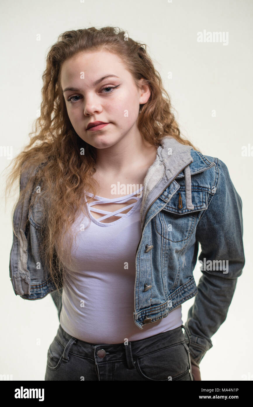 A moody attrractive young 13 thirteen year old teenage adolescent girl wearing a denim jacket, looking moody,  , UK Stock Photo