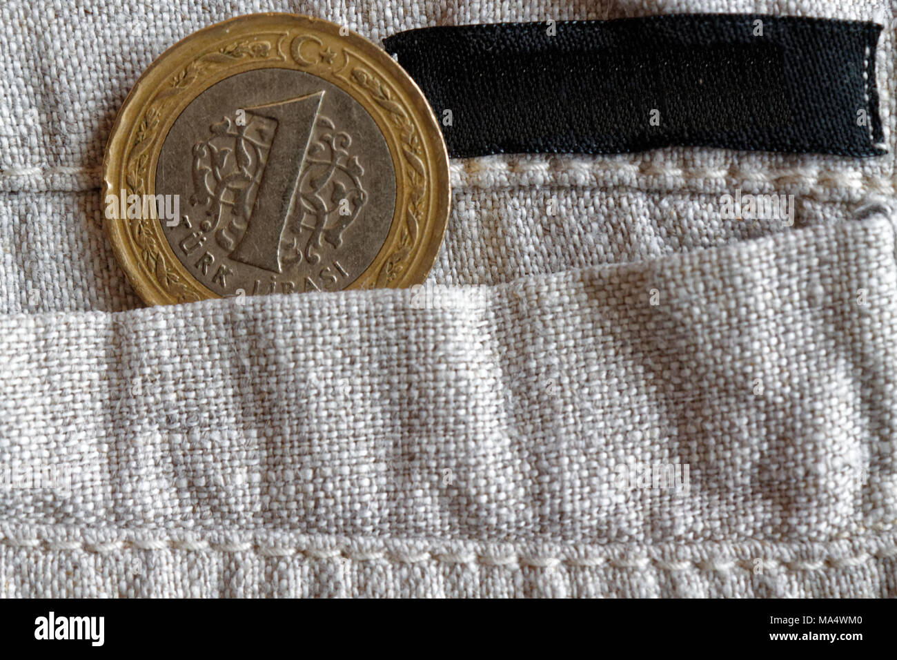 Turkish coin with a denomination of one lira in the pocket of old linen pants empty black stripe for label Stock Photo
