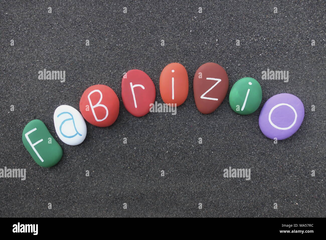 Fabrizio, masculine given name with multicolored stones over black volcanic sand Stock Photo