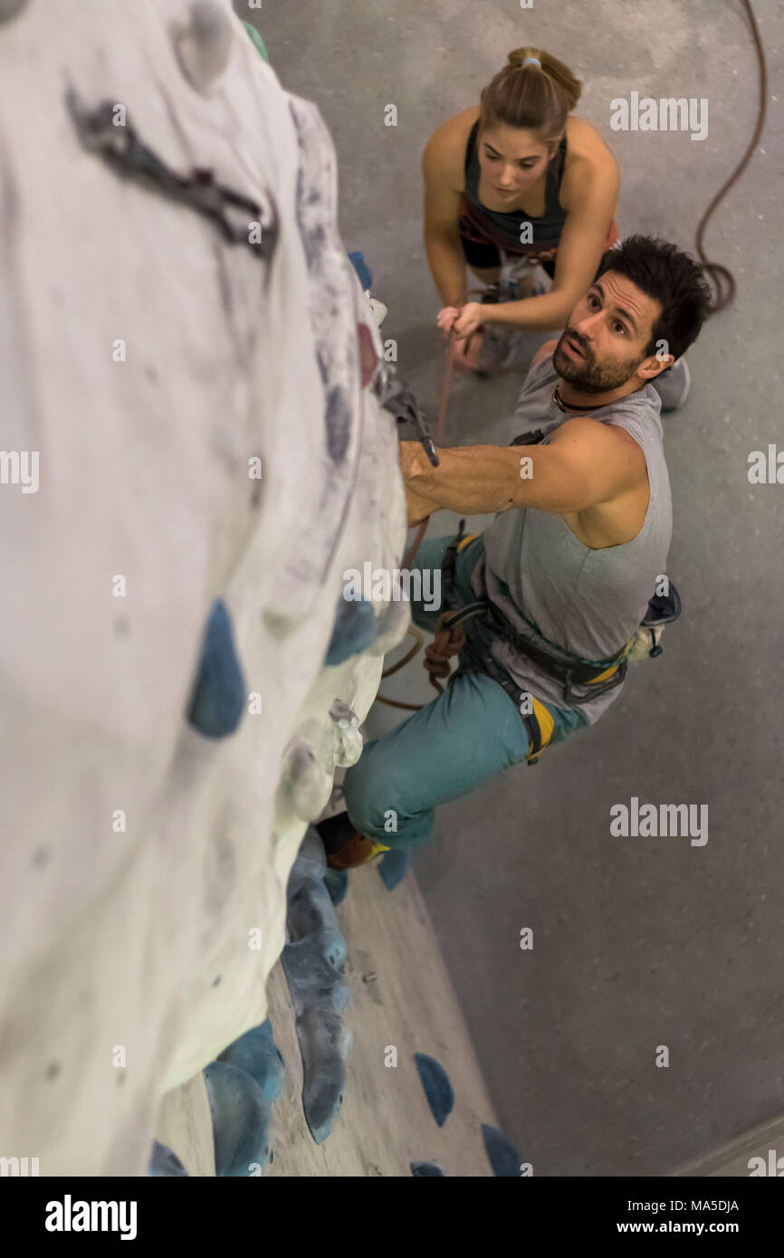 Climbing trainer in the lead secured by young climber hires stock