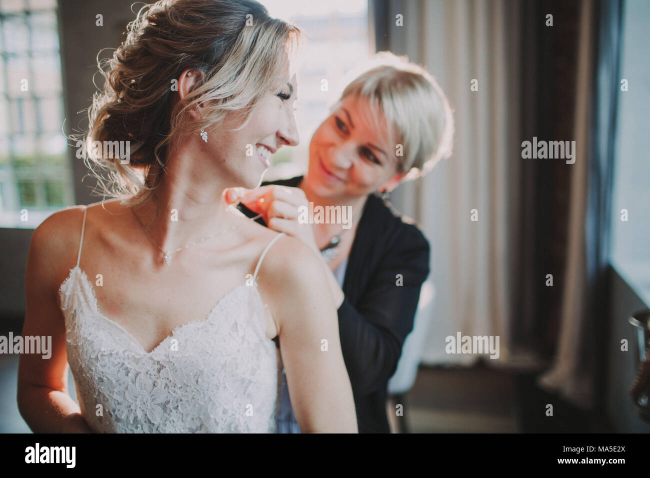 Stylist puts a necklace to the bride Stock Photo