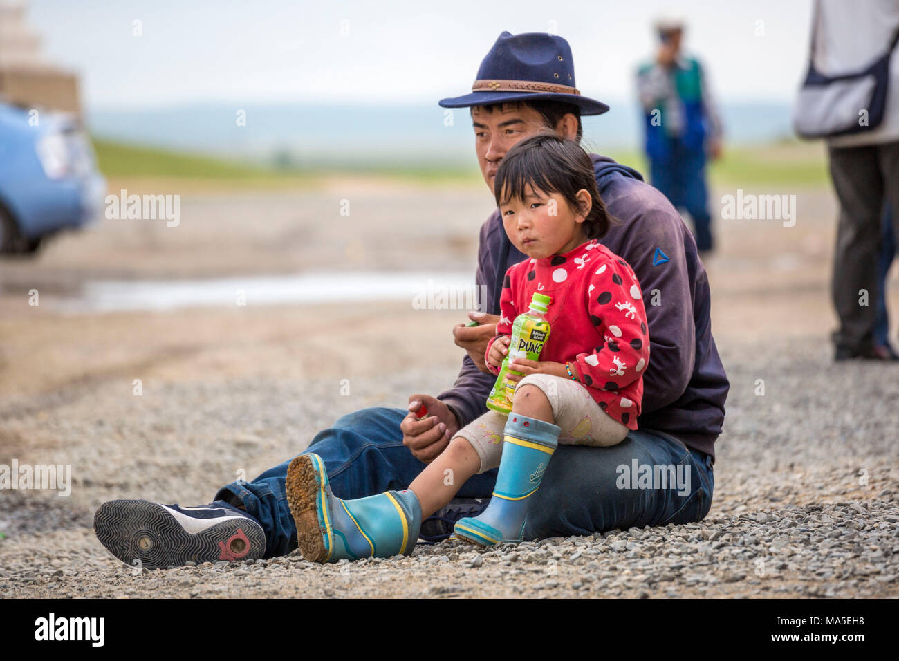 Father and daughter sitting on the ground. Harhorin, South Hangay province, Mongolia. Stock Photo
