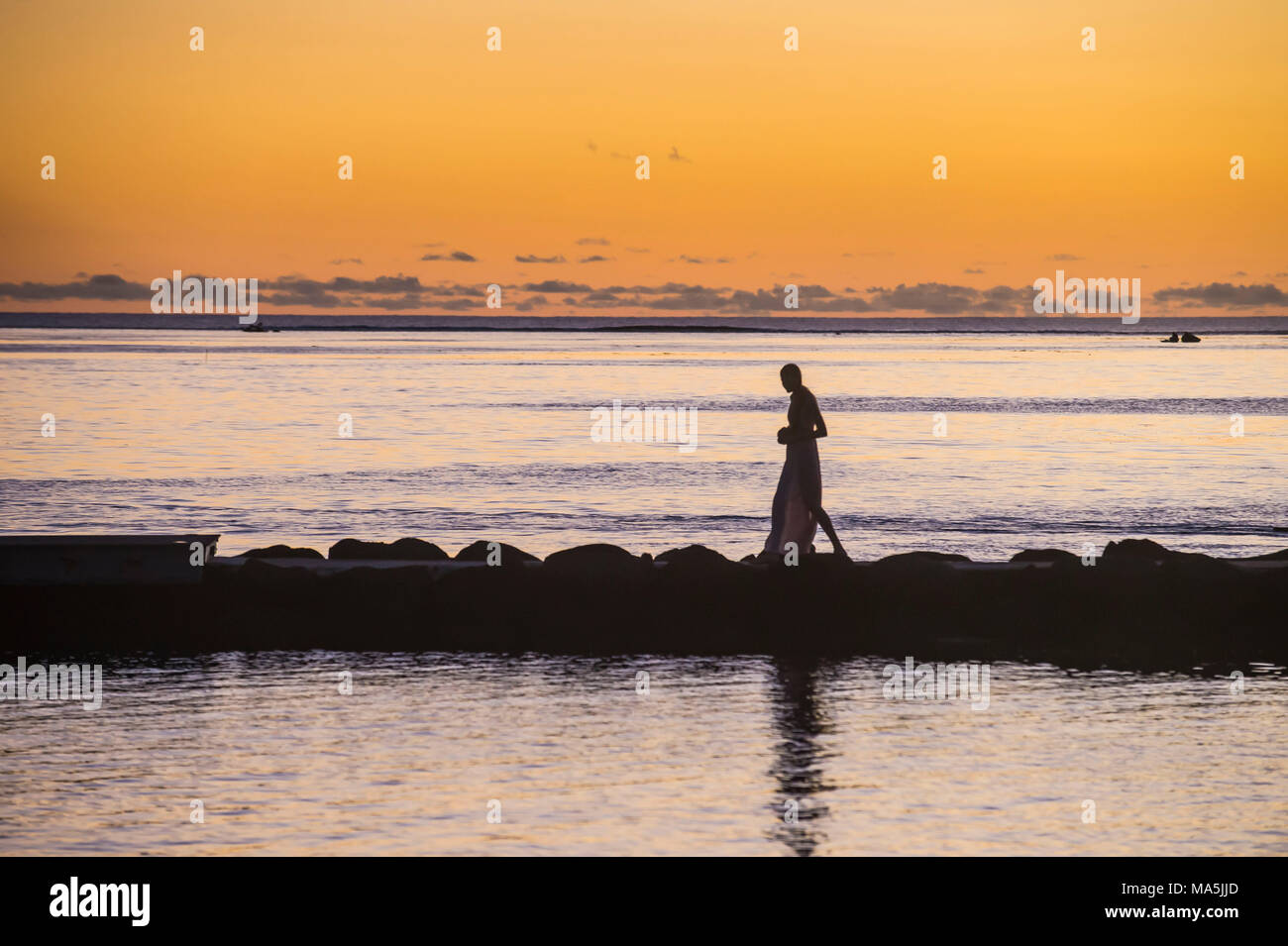 Woman walking on a pier at sunset, Papeete, Tahiti, French Polynesia Stock Photo