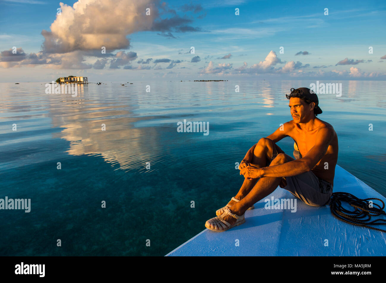 Man sitting on his boat over  the calm waters of Tikehau, Tuamotus, French Polynesia Stock Photo