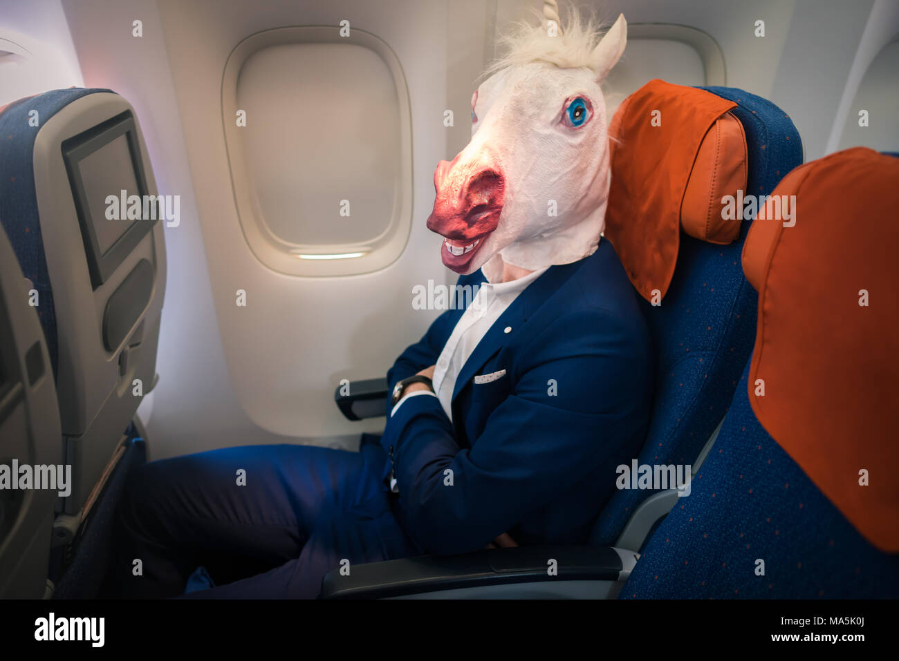 Strange passenger in elegant suit sits alone inside the aircraft and ready to take off. Unusual traveler in air voyage. Stock Photo