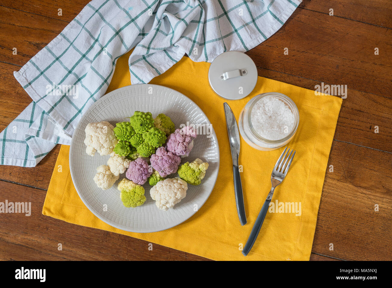 White, pink and green cauliflower on a plate on a wooden table Stock Photo