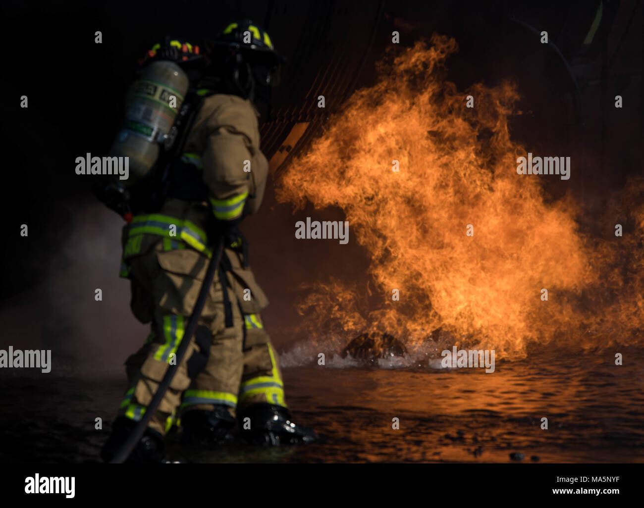 Airman 1st Class Alessandre Nagano, 2nd Civil Engineering Squadron firefighter, and Staff Sgt. Joseph Chavez, 2nd CES fire department crew chief, extinguish a fire during a live burn training exercise at Barksdale Air Force Base, La., March 21, 2018. During these exercises, the fires are fueled by propane and controlled by personnel at all times. (U.S. Air Force photo by Airman 1st Class Tessa B. Corrick) Stock Photo