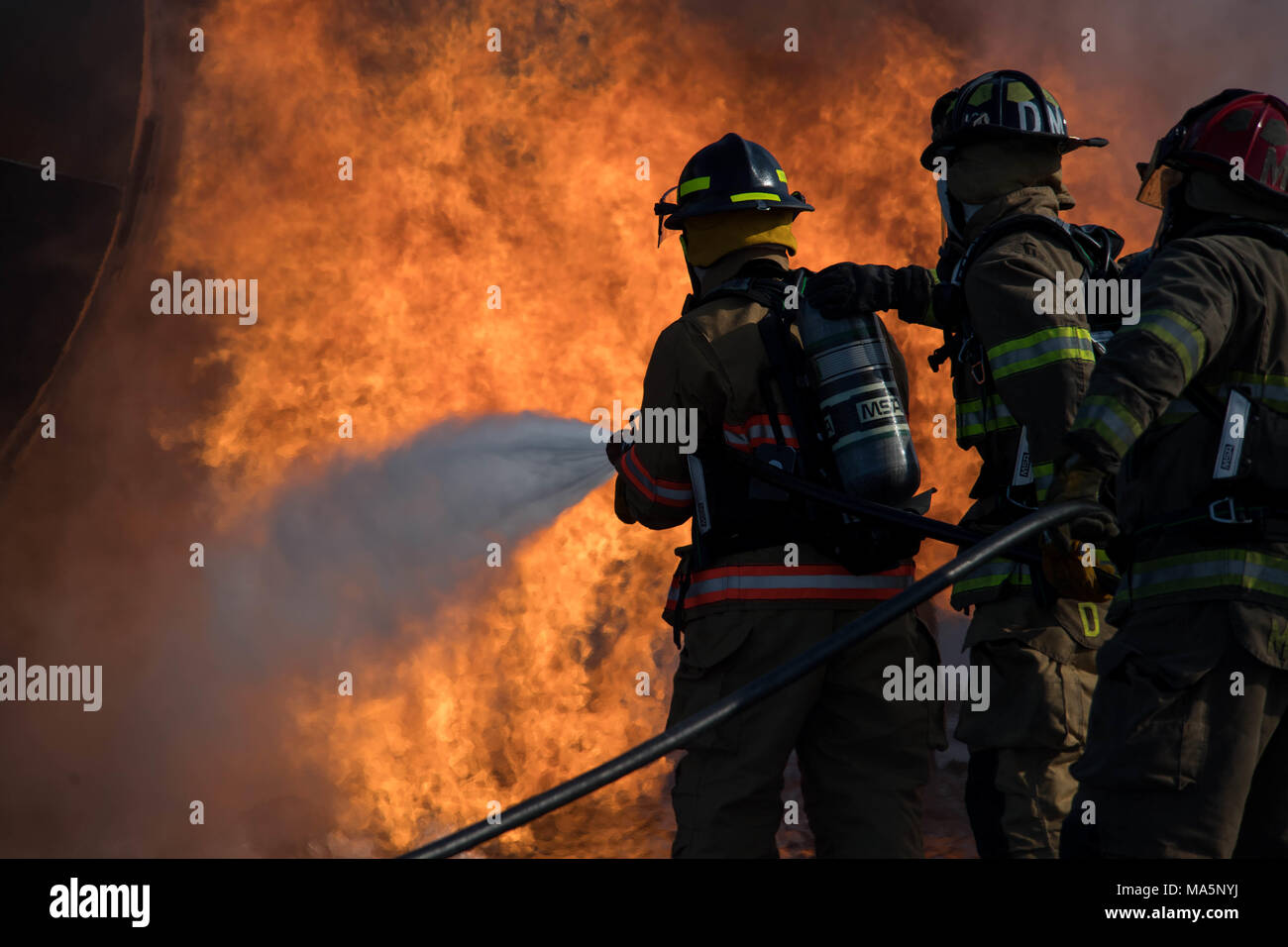 Engineer Ross Dees, Captain Marcus Houston and Engineer DeMarcus Murray, Shreveport Fire Department firefighters, extinguish a fire during an annual recertification burn at Barksdale Air Force Base, La., March 20, 2018.  The Federal Aviation Administration requires SFD firefighters to complete this training annually to ensure personnel are proficient in techniques and required duties. (U.S. Air Force photo by Airman 1st Class Tessa B. Corrick) Stock Photo