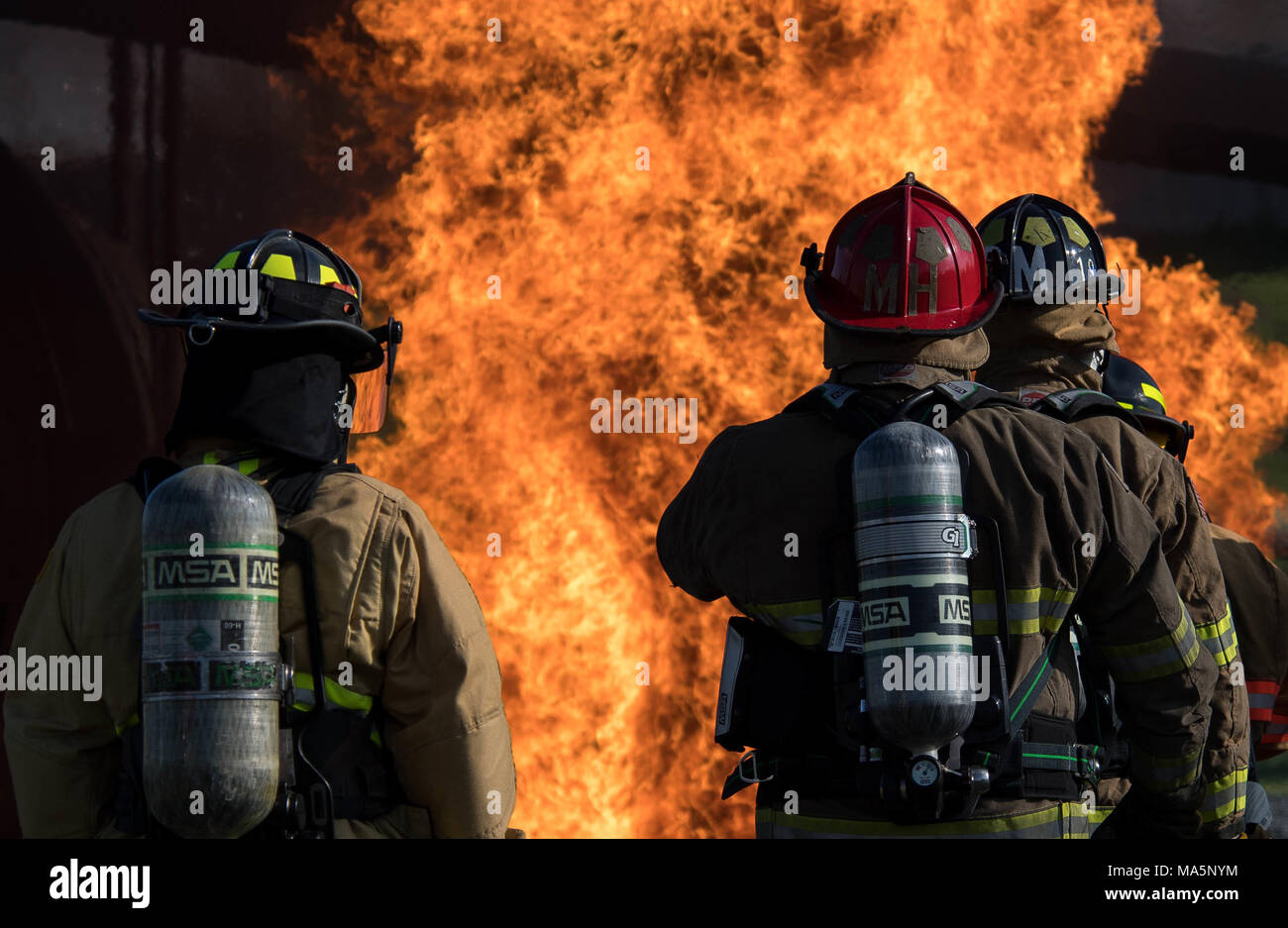 A firefighter assigned to the 2nd Civil Engineering Squadron, Captain Marcus Houston and Engineer DeMarcus Murray, Shreveport Fire Department firefighters, prepare to extinguish a fire during an annual recertification burn at Barksdale Air Force Base, La., March 20, 2018. Barksdale hosted the SFD for their annual re-certification exercise, which simultaneously fulfilled an annual requirement for themselves. (U.S. Air Force photo by Airman 1st Class Tessa B. Corrick) Stock Photo