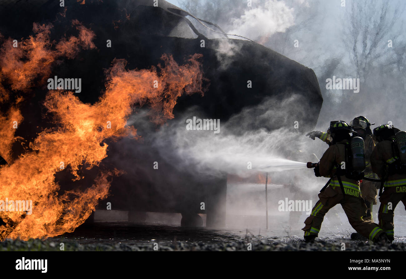 Airmen 1st Class Alessandre Nagano and DeVaundre Carmona, 2nd Civil Engineering Squadron firefighters, and Jonathan Rapelje, 2nd CES lead firefighter, extinguish a fire during a live burn training exercise at Barksdale Air Force Base, La., March 20, 2018. During these exercises, the fires are fueled by propane and controlled by personnel at all times. (U.S. Air Force photo by Airman 1st Class Tessa B. Corrick) Stock Photo