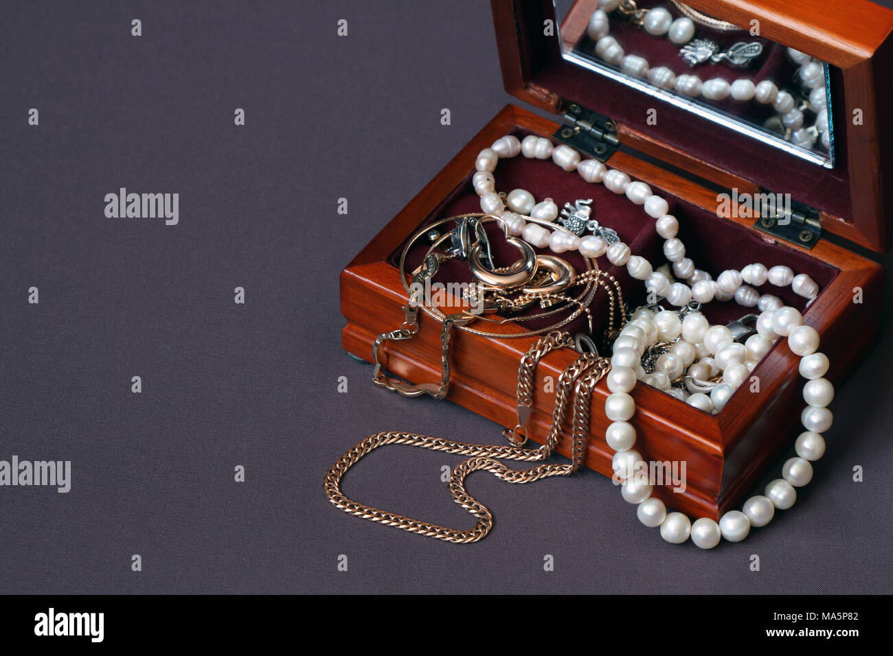Nice wooden jewelry box on dark textiles background with copy space