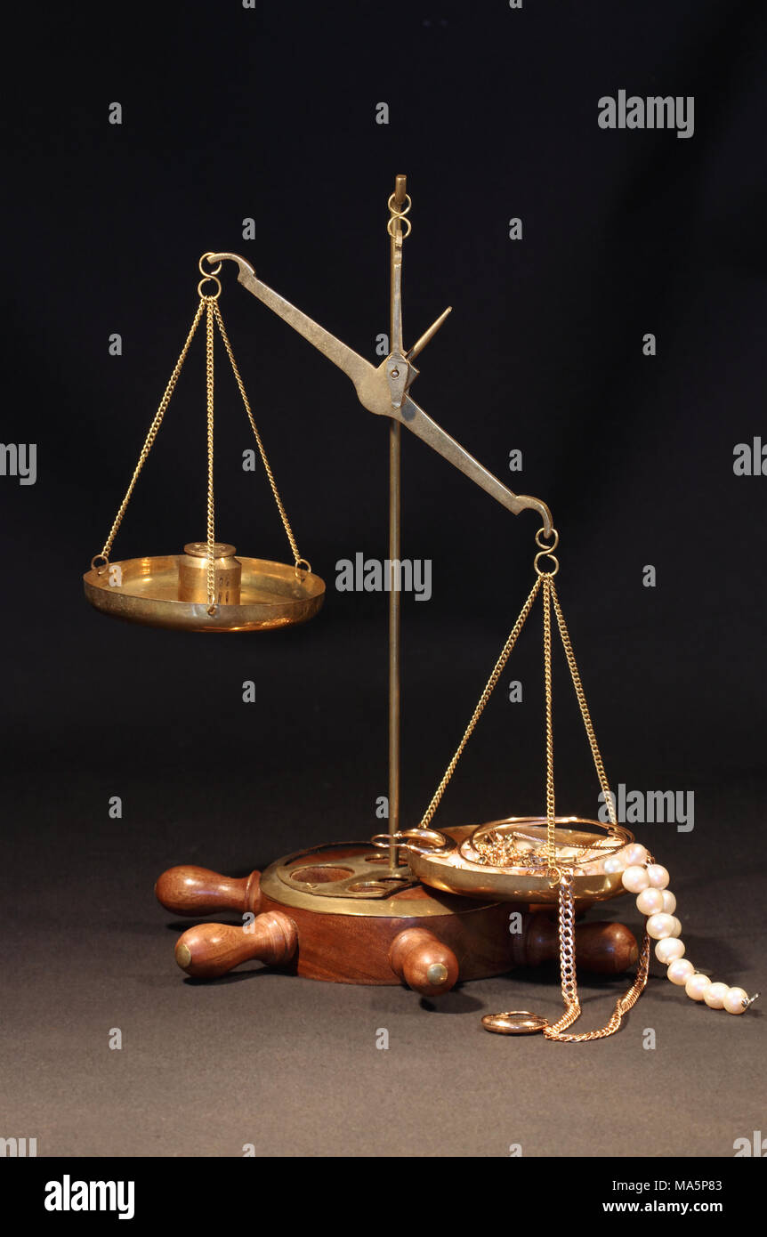 Old brass weight scale with various jewelry on dark background Stock Photo