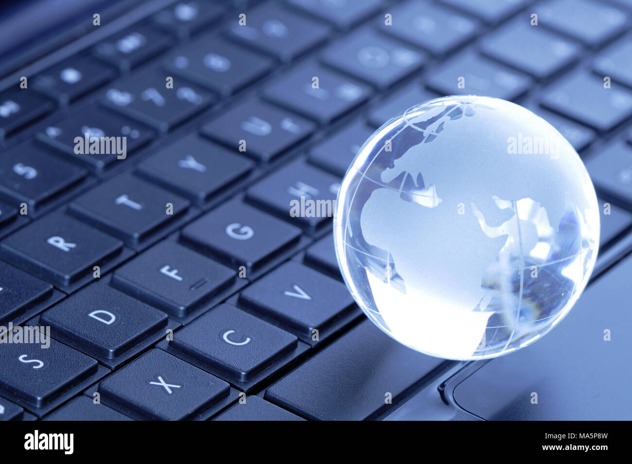 Glass globe lying on black laptop computer keyboard Stock Photo - Alamy