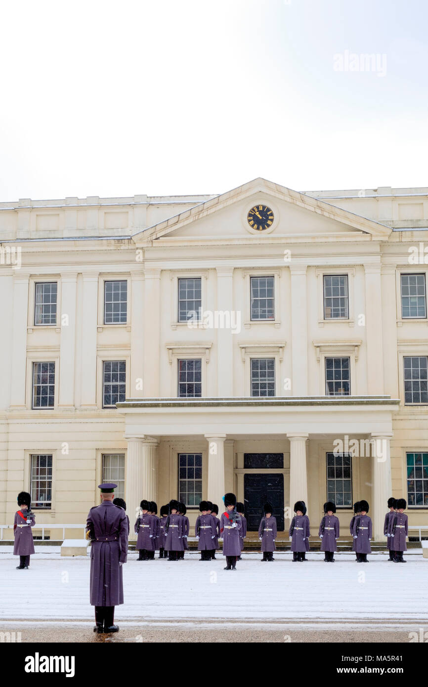 Irish guards from the Queens Guard regiments preparing for the Changing of the Guard ceremony with an inspection in the snow at Wellington Barracks Stock Photo
