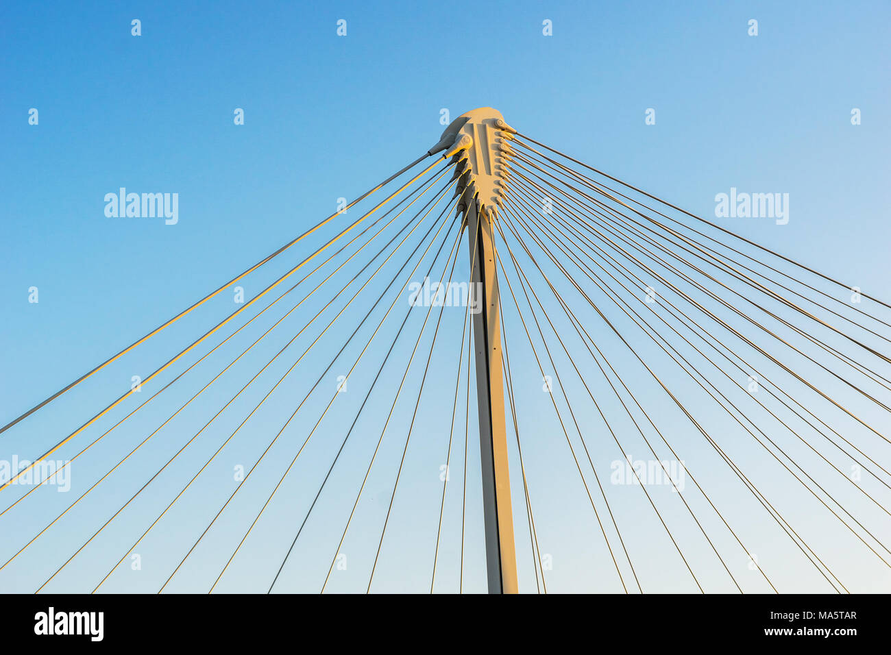 Detail of the structure of a cable-stayed bridge with the column and the guy wires isolated on a blue sky. Team and network concept. Stock Photo