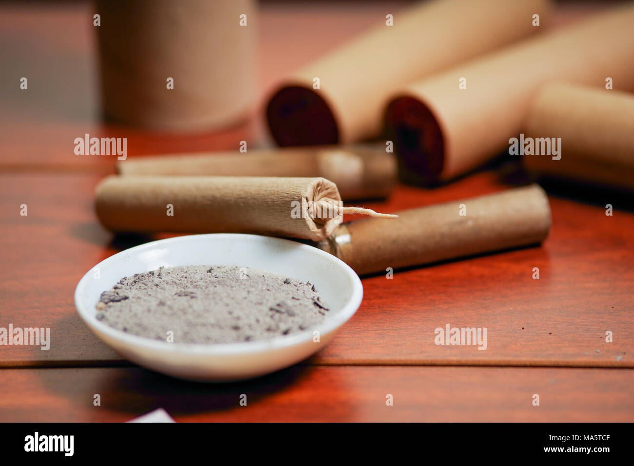 Close up of brown firecrackers close to a white bowl with gunpowder, over a  wooden table Stock Photo