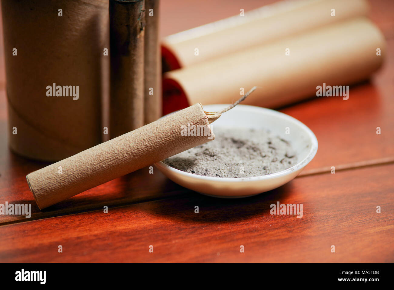 Close up of brown firecrackers close to a white bowl with gunpowder, over a  wooden table Stock Photo