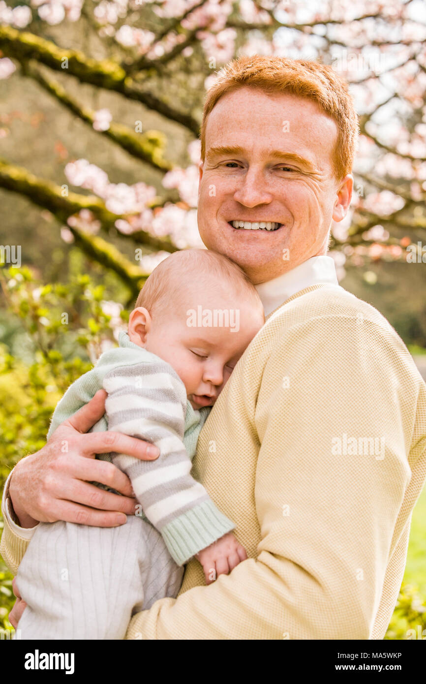 A portrait of a father with his 10 month old son outdoors in a Spring like location. Stock Photo