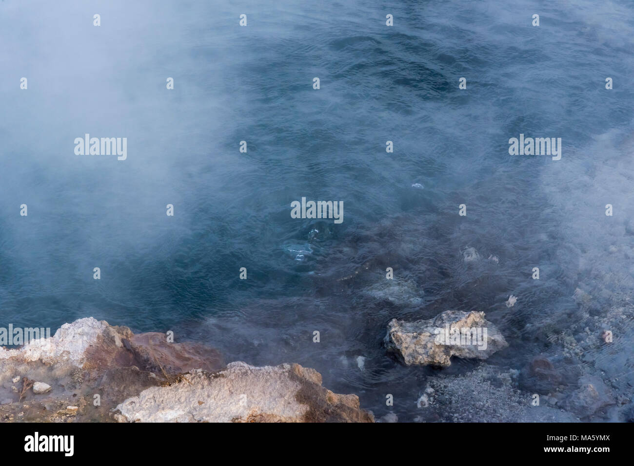 Boiling hot spring with steam rising up off the surface of the water. Stock Photo