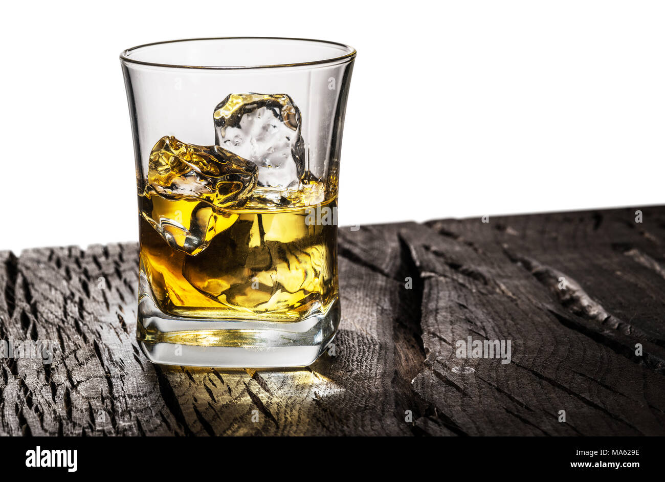 Whiskey glass or glass of whiskey with ice cubes on table at the white background. Stock Photo