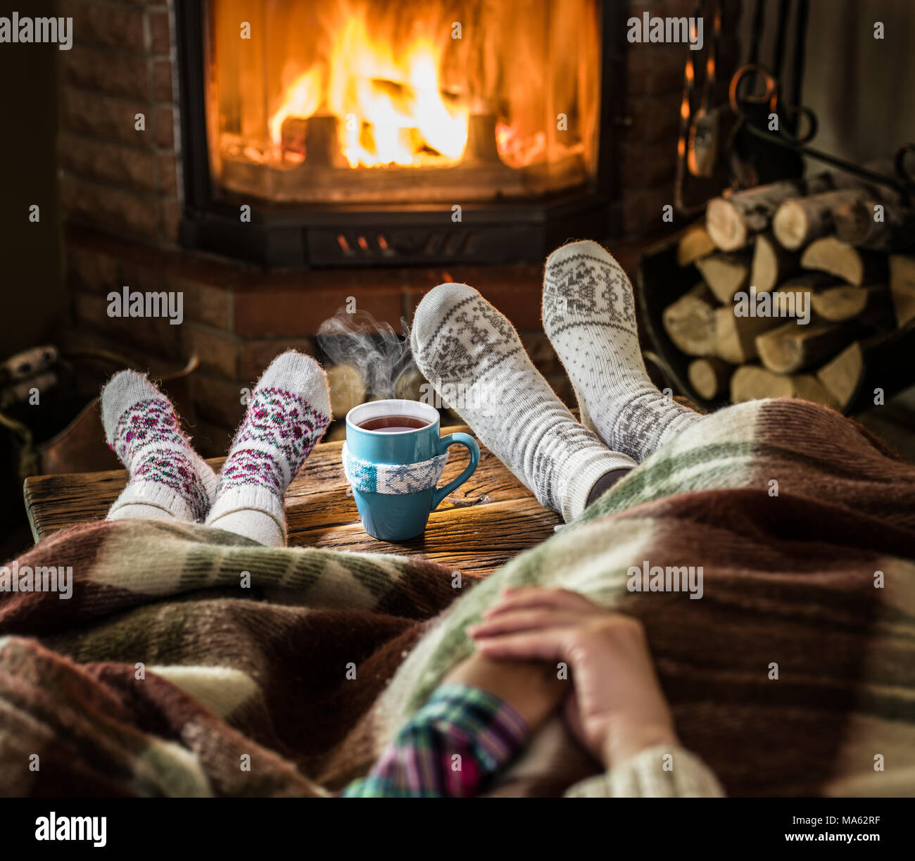Warming and relaxing near fireplace. Mother and daughter holding hands