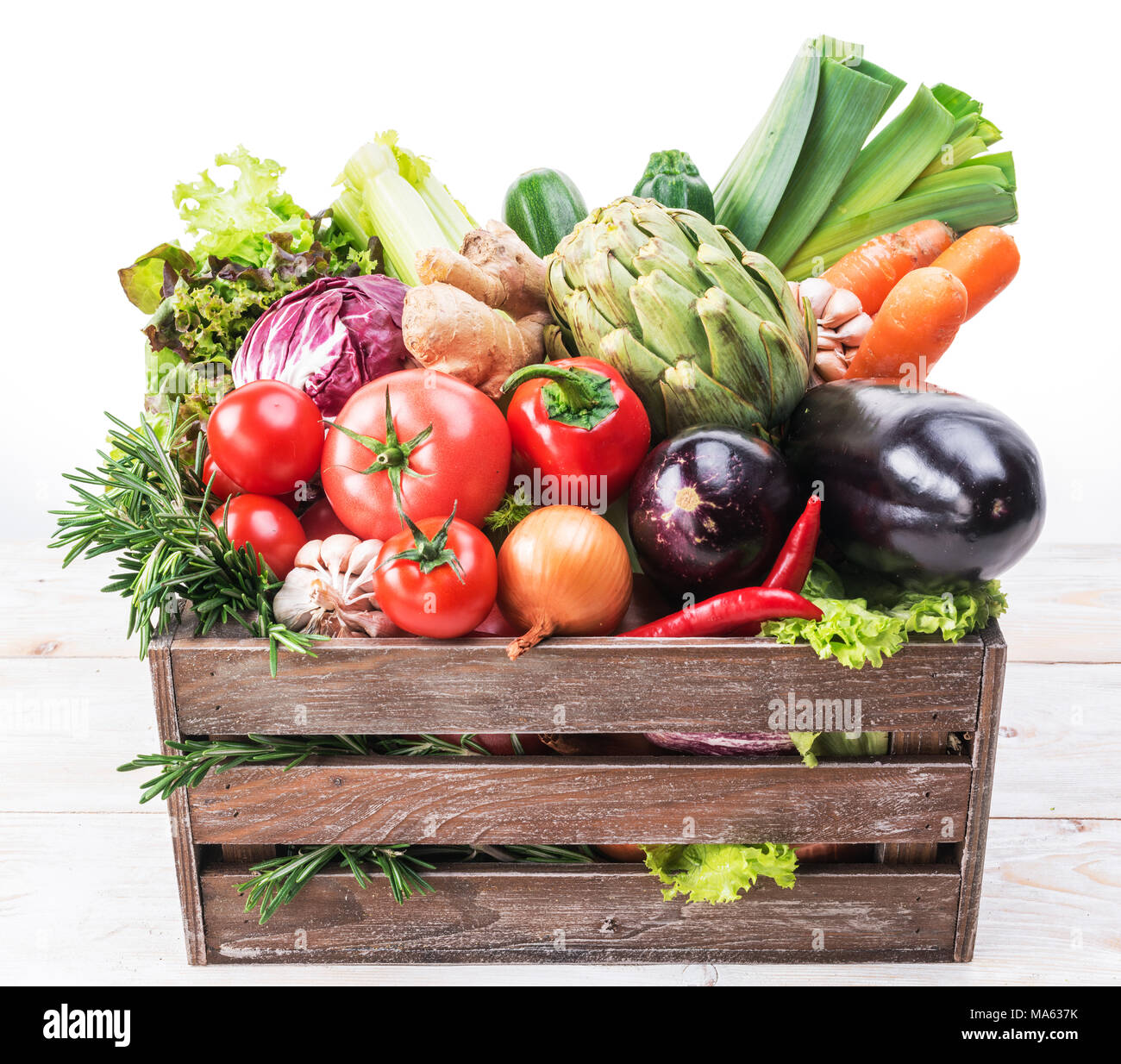 Fresh multi-colored vegetables in wooden crate. White background. Stock Photo