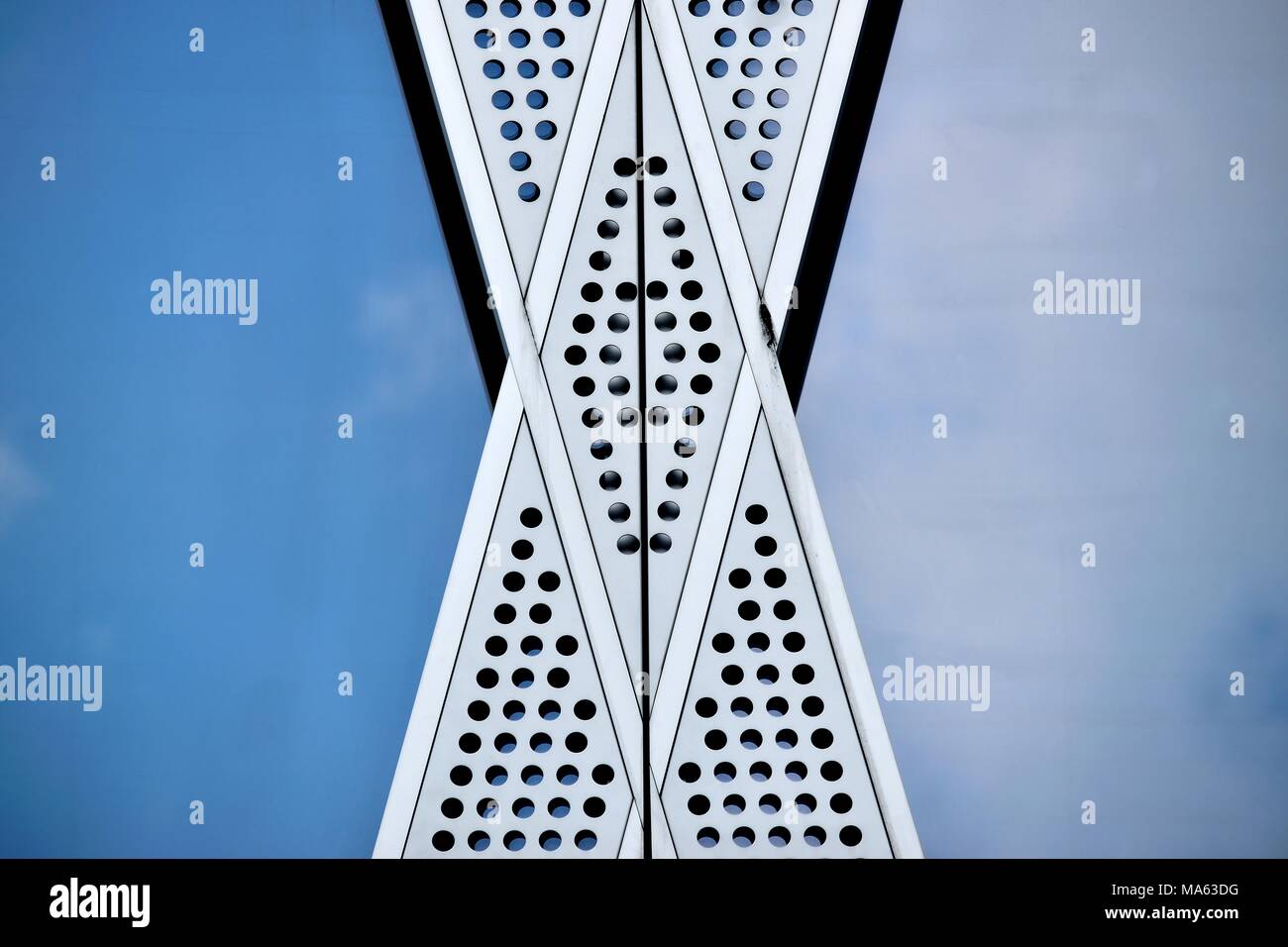 Close up of diagonal aluminum cladding on a modern office building with glass panels reflecting blue sky as abstract background with space for copy. Stock Photo