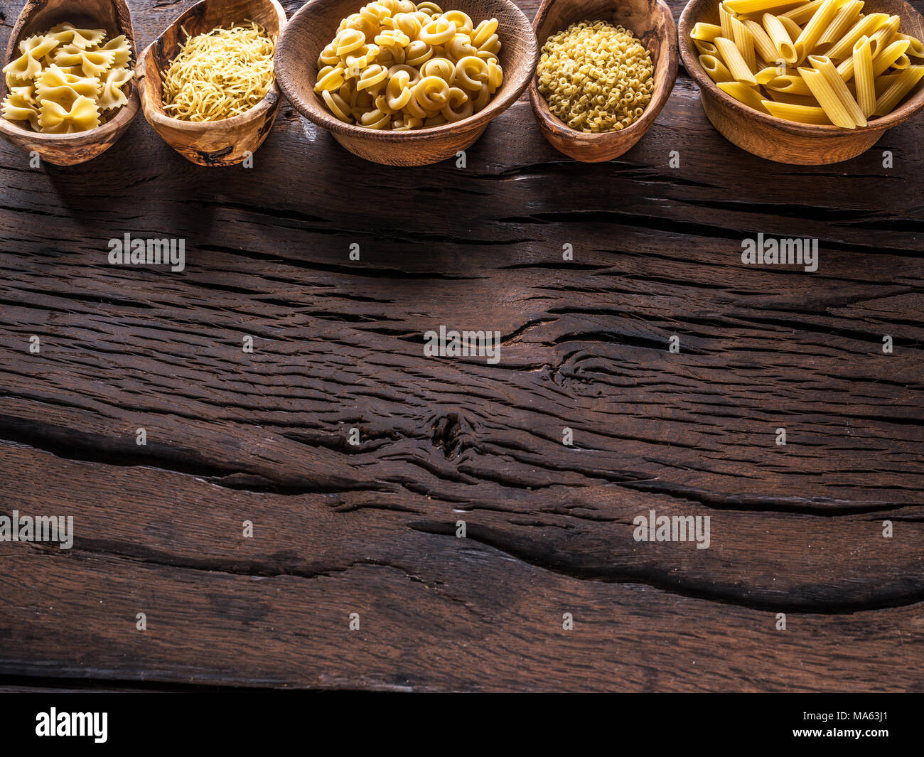 Different pasta types in wooden bowls on the table. Top view. Stock Photo