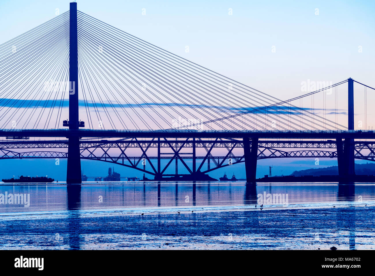 Sunrise view of the three major bridges crossing the Firth of Forth at South Queensferry; Queensferry Crossing, North Road Bridge and the Forth Bridge Stock Photo