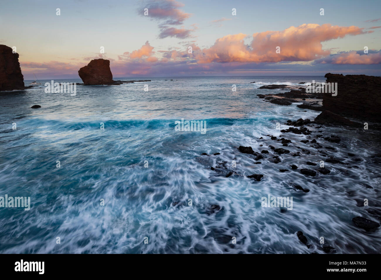 Sunset light on the clouds above Puu Pehe Rock, also known as “Sweetheart Rock”, one of Lanai’s most recognizable landmarks, Lanai Island, Hawaii, USA Stock Photo