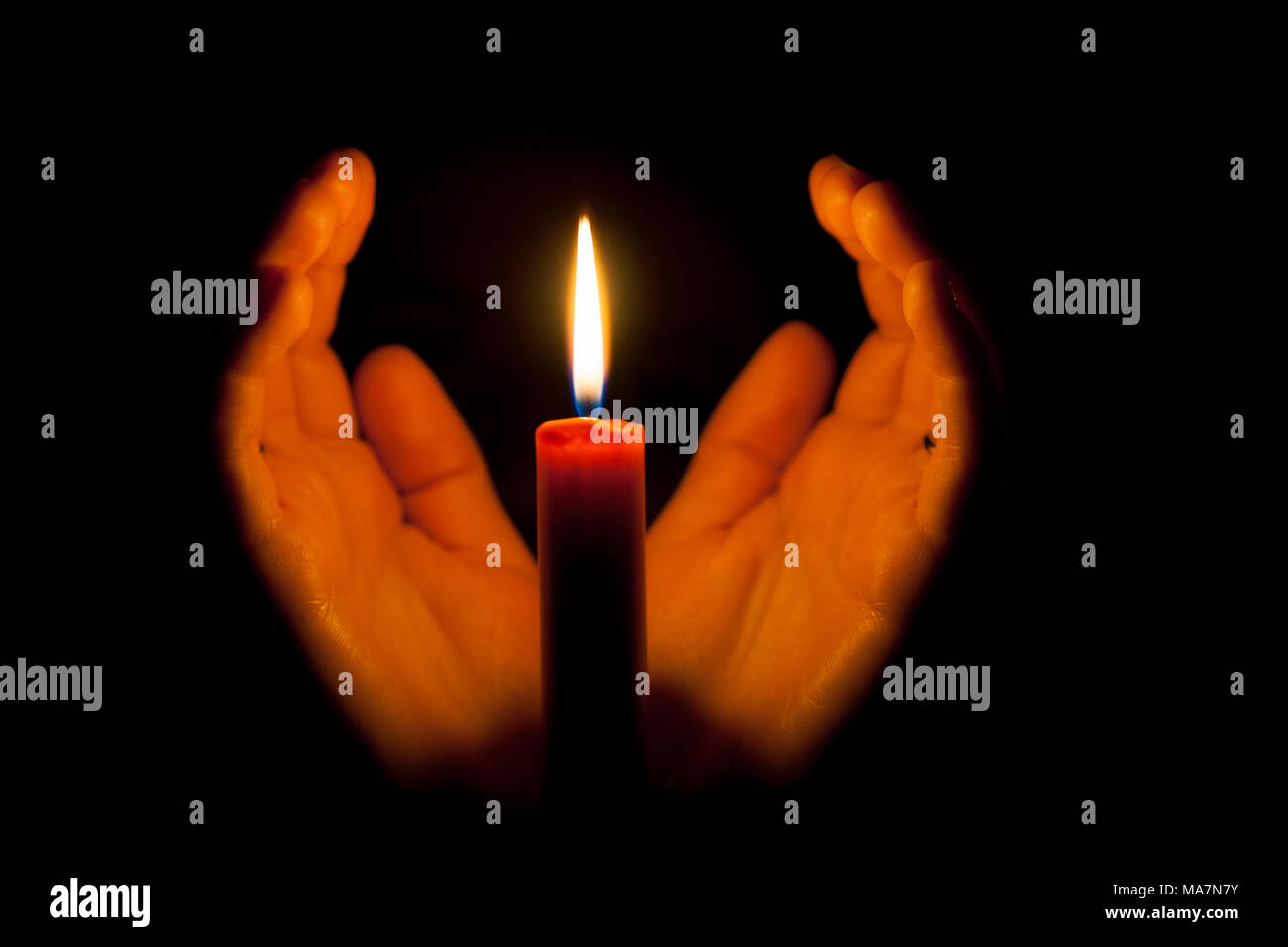 A burning candle at night, surrounded by the hands of a woman. Candle flame  glowing on a dark background with free space for text. Close up, shallow d  Stock Photo - Alamy